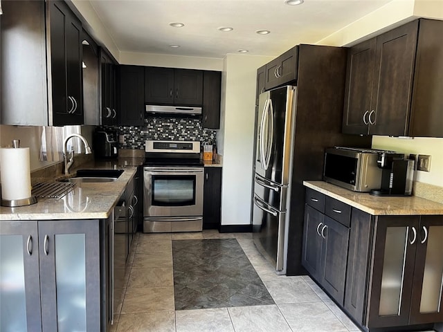 kitchen featuring appliances with stainless steel finishes, dark brown cabinets, sink, backsplash, and light tile patterned floors