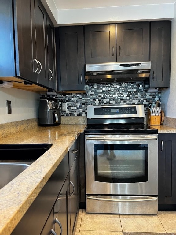 kitchen with light tile patterned flooring, decorative backsplash, light stone countertops, and stainless steel electric stove