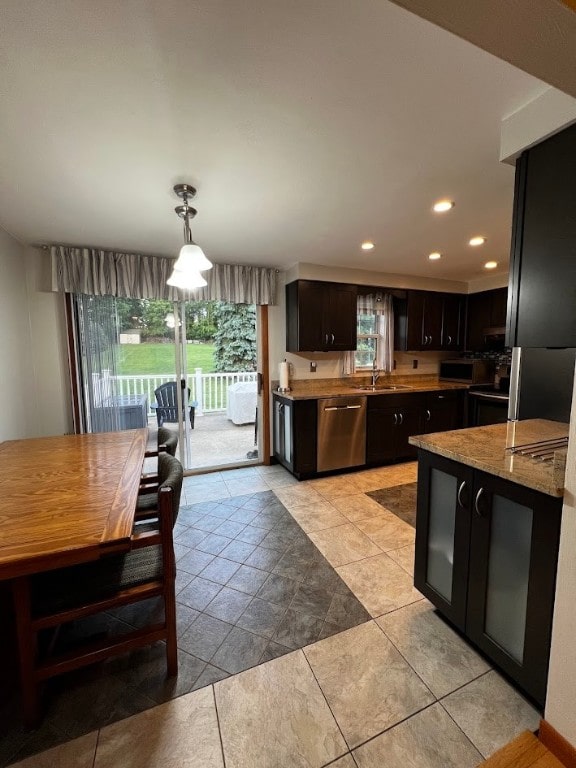 kitchen with light tile patterned flooring, sink, stainless steel appliances, and decorative light fixtures