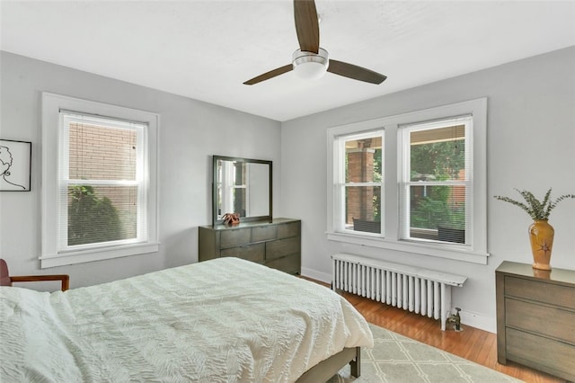 bedroom featuring ceiling fan, radiator heating unit, and light wood-type flooring