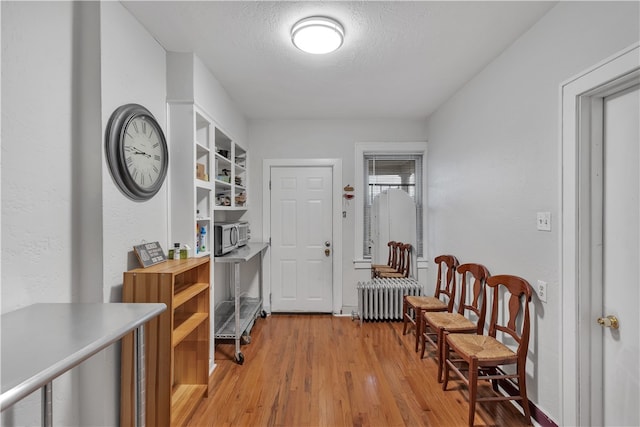 interior space with radiator heating unit, a textured ceiling, and light hardwood / wood-style flooring