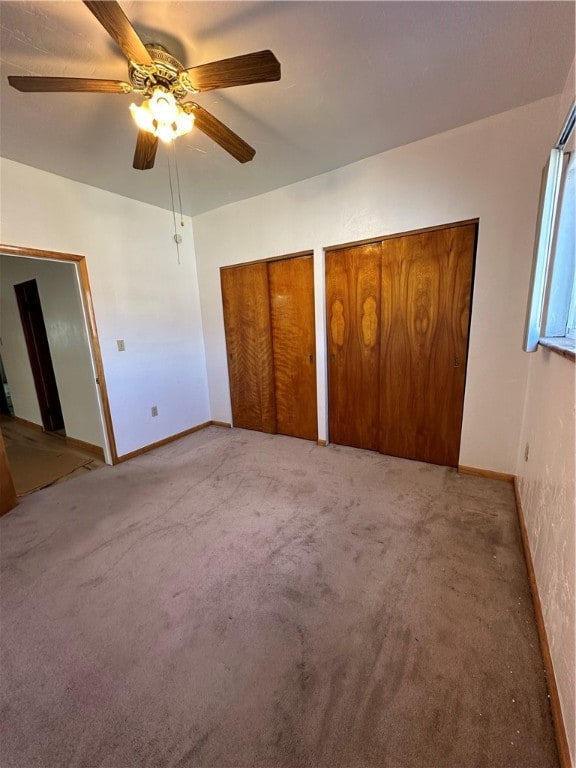 unfurnished bedroom featuring two closets, carpet, and ceiling fan