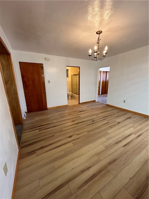 interior space with an inviting chandelier, hardwood / wood-style floors, and ensuite bath