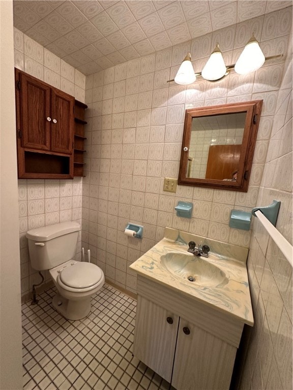 bathroom with tile walls, toilet, tile floors, and large vanity