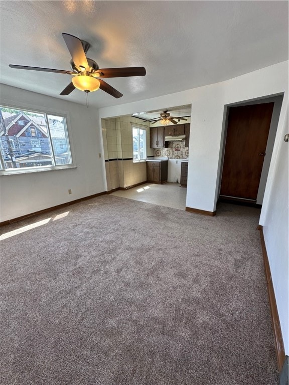 unfurnished living room featuring carpet, ceiling fan, and a healthy amount of sunlight