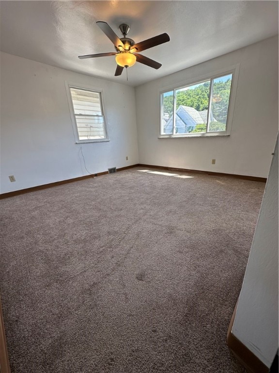 spare room with ceiling fan and dark colored carpet