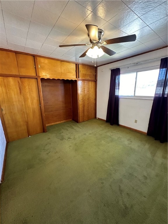 unfurnished bedroom with carpet flooring, wood walls, a closet, and ceiling fan