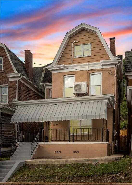 back house at dusk featuring ac unit and covered porch