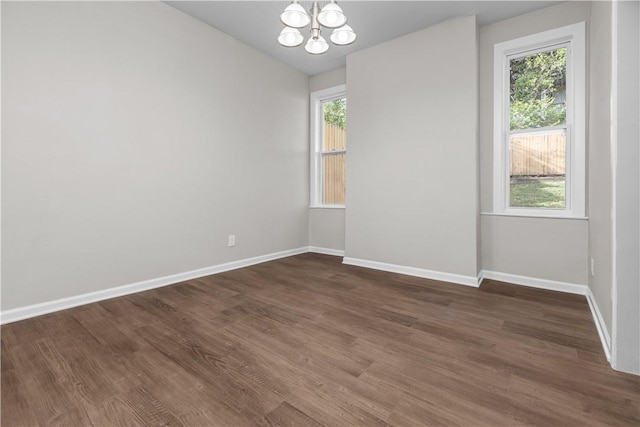 spare room featuring an inviting chandelier, lofted ceiling, and dark hardwood / wood-style floors