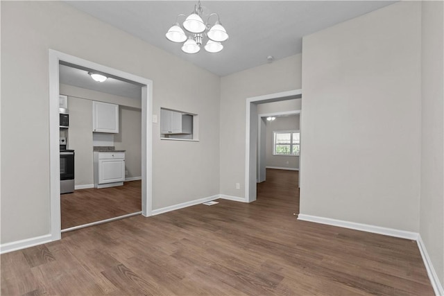 unfurnished dining area with wood-type flooring and a notable chandelier