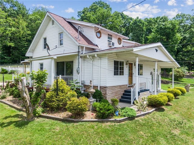 rear view of property featuring covered porch and a lawn