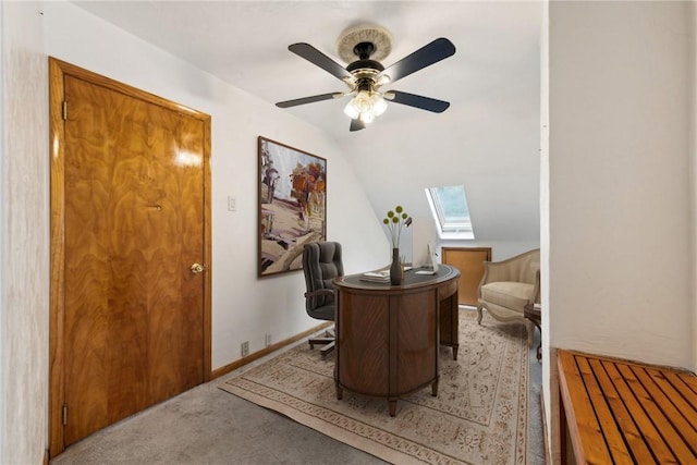 office featuring ceiling fan, vaulted ceiling with skylight, and light carpet