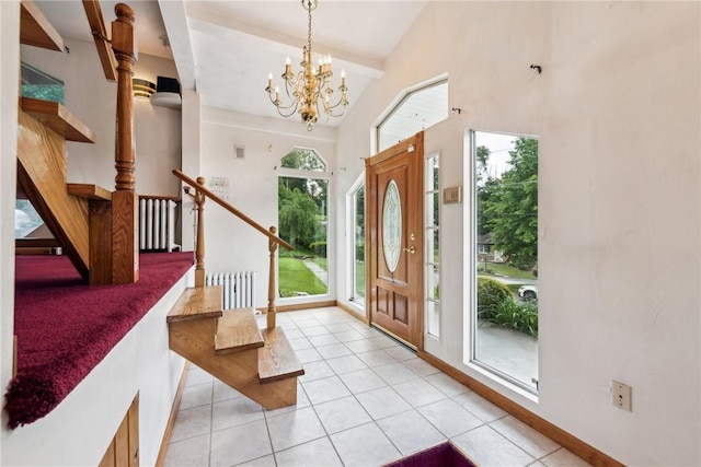 tiled entryway with a healthy amount of sunlight, radiator, vaulted ceiling, and a notable chandelier