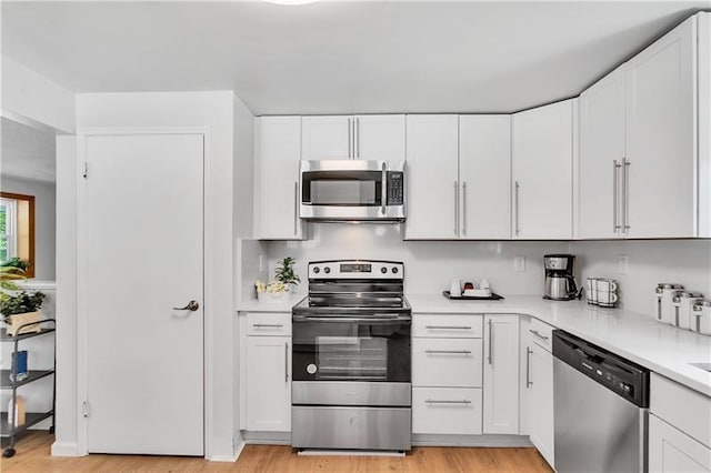 kitchen featuring white cabinets, light wood-type flooring, and stainless steel appliances