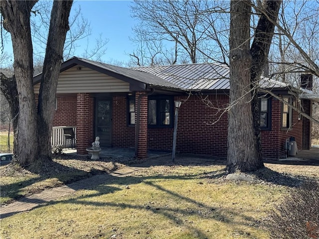 view of front of property featuring a standing seam roof, a front yard, brick siding, and metal roof