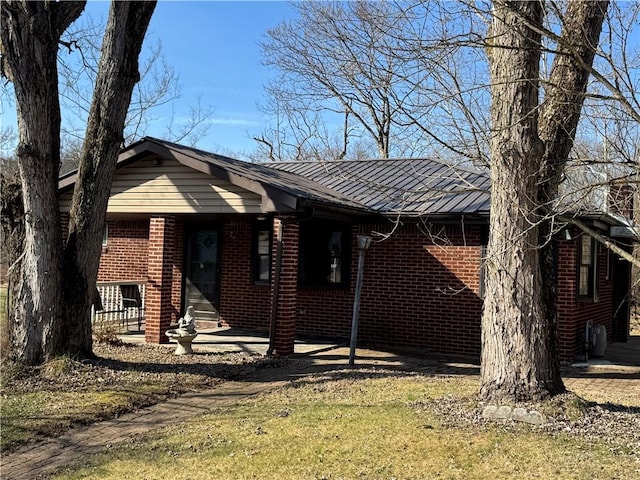 view of front of house featuring brick siding, entry steps, metal roof, and a standing seam roof