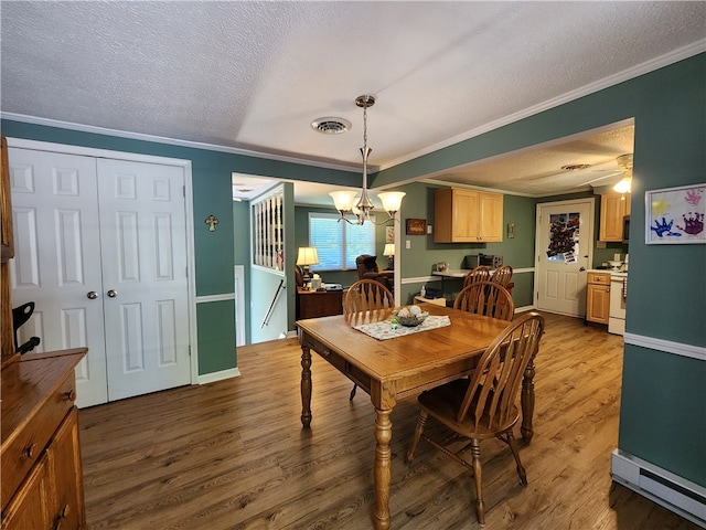 dining area featuring a textured ceiling, hardwood / wood-style floors, ornamental molding, and a chandelier