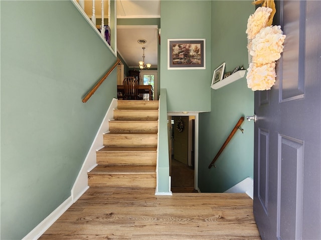 stairway featuring hardwood / wood-style floors and an inviting chandelier