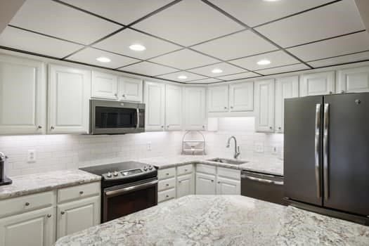 kitchen with white cabinetry, sink, stainless steel appliances, light stone counters, and decorative backsplash