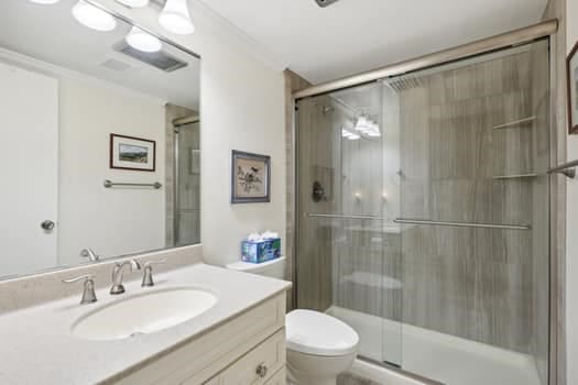 bathroom featuring walk in shower, crown molding, vanity, and toilet