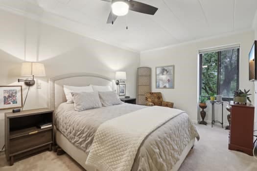 carpeted bedroom with ceiling fan and ornamental molding