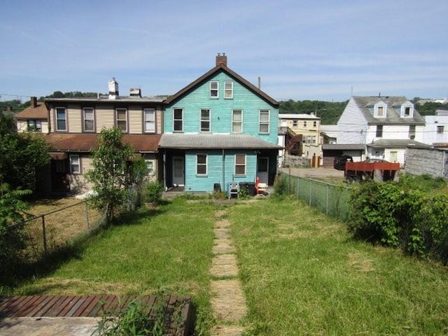 rear view of property with fence and a lawn