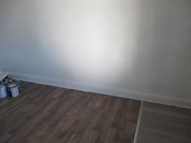 spare room featuring baseboards and dark wood-style flooring