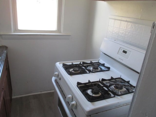 kitchen with dark wood-type flooring, light countertops, gas range gas stove, and baseboards