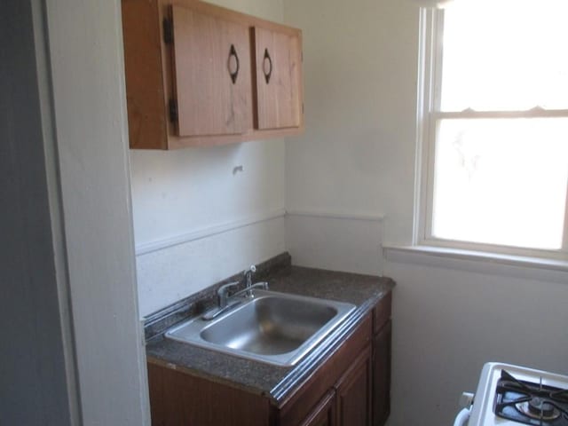 kitchen with dark countertops, range, brown cabinets, and a sink