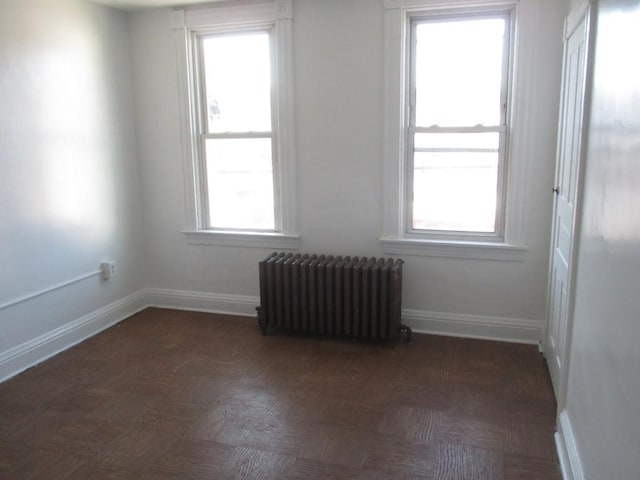 empty room with radiator heating unit and baseboards