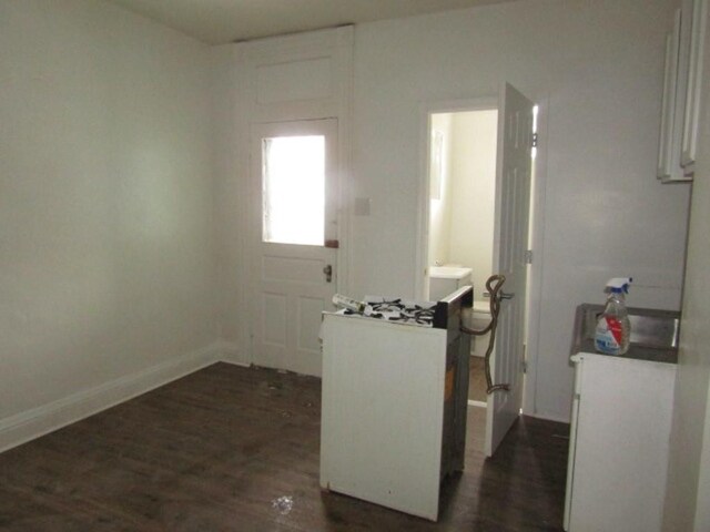 interior space with baseboards, white cabinets, and dark wood-style flooring