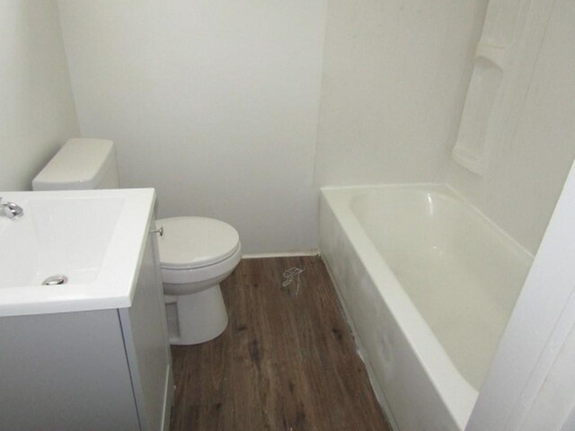 bathroom featuring a bath, vanity, toilet, and wood finished floors