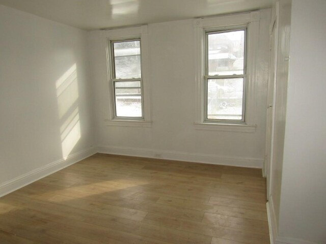 unfurnished room featuring baseboards and light wood-style floors