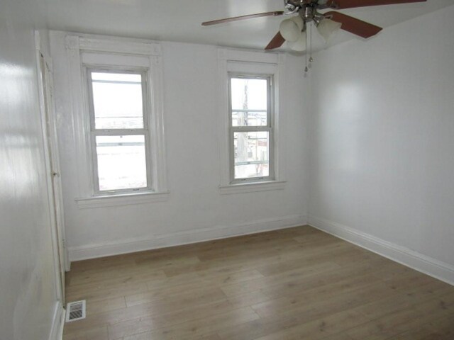 unfurnished room with light wood-type flooring, visible vents, plenty of natural light, and baseboards