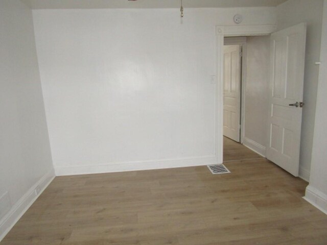 spare room with baseboards, visible vents, and light wood finished floors