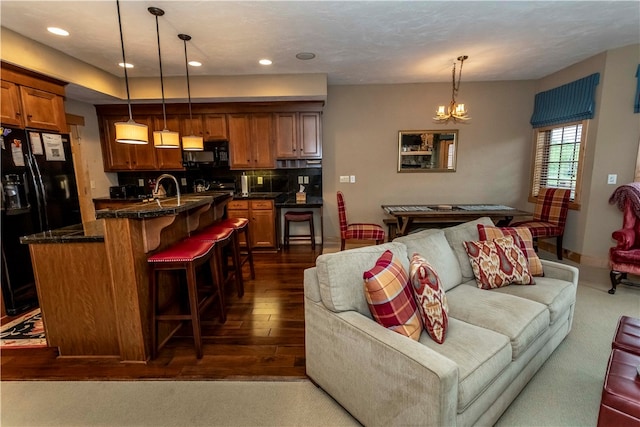 living room featuring an inviting chandelier, sink, and dark hardwood / wood-style flooring