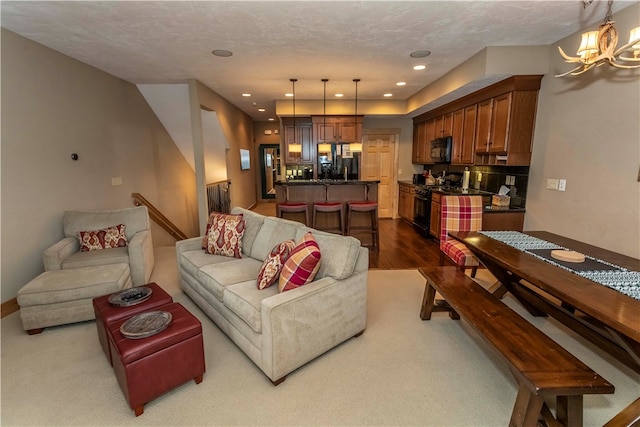 carpeted living room featuring an inviting chandelier and a textured ceiling