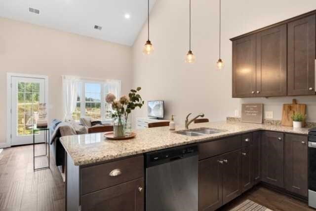 kitchen with appliances with stainless steel finishes, high vaulted ceiling, kitchen peninsula, decorative light fixtures, and dark hardwood / wood-style floors