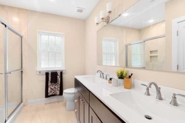 bathroom featuring vanity, toilet, and an enclosed shower