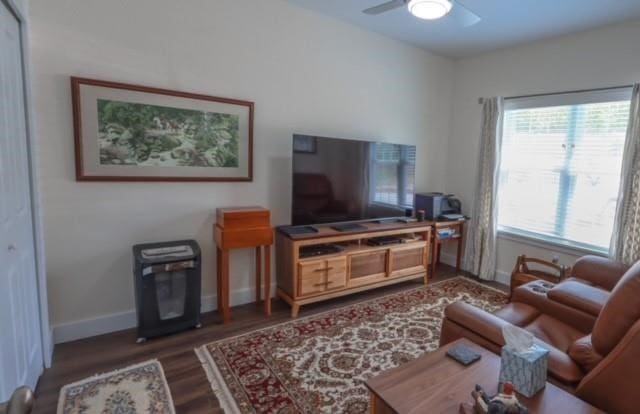 living room with ceiling fan and dark hardwood / wood-style flooring