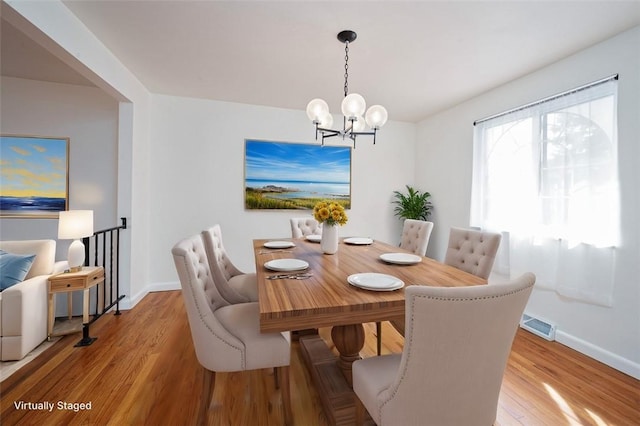 dining area with an inviting chandelier, wood finished floors, baseboards, and visible vents