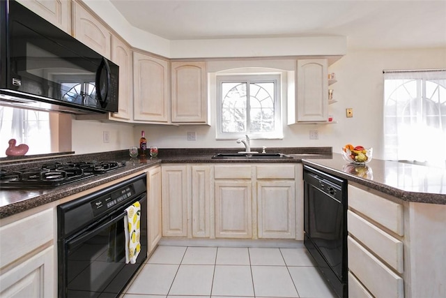 kitchen featuring light brown cabinetry, a peninsula, plenty of natural light, black appliances, and a sink