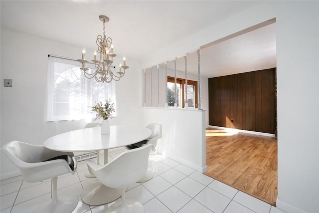 tiled dining area featuring baseboards, an inviting chandelier, and wood walls