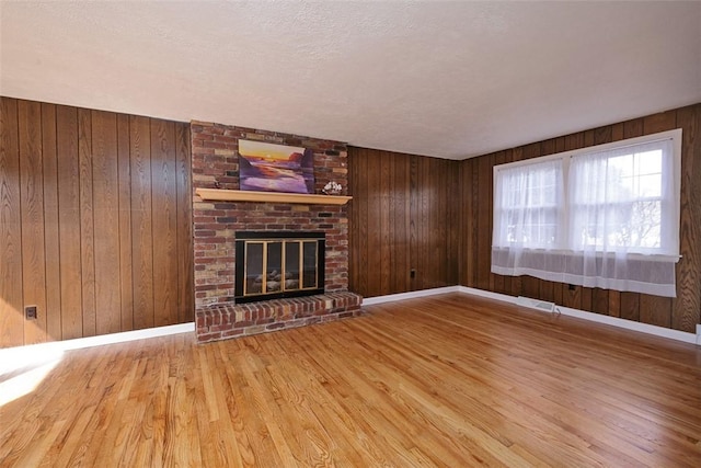 unfurnished living room featuring wooden walls, wood finished floors, visible vents, baseboards, and a fireplace