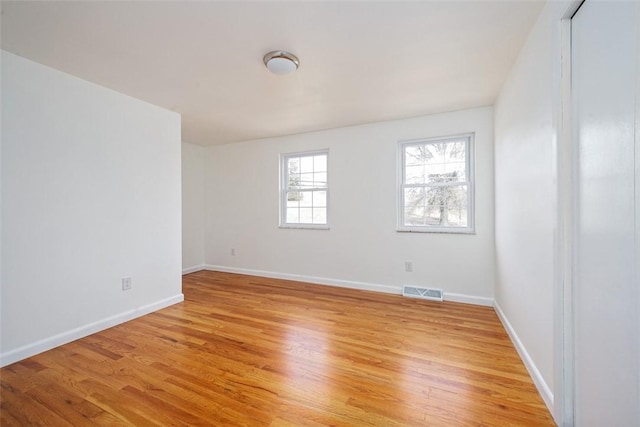 spare room featuring visible vents, light wood-style flooring, and baseboards