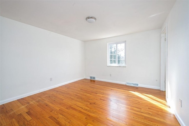 empty room featuring visible vents, baseboards, and light wood-style flooring