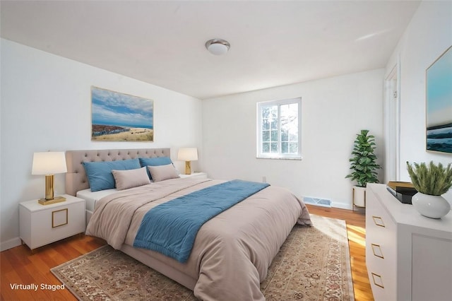 bedroom featuring visible vents, light wood-type flooring, and baseboards