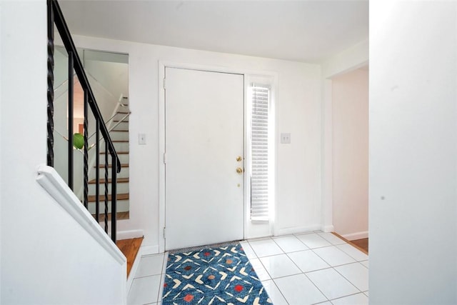 tiled entrance foyer with stairway and baseboards