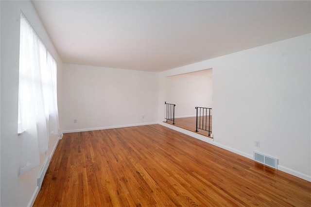 spare room featuring visible vents, baseboards, and wood finished floors