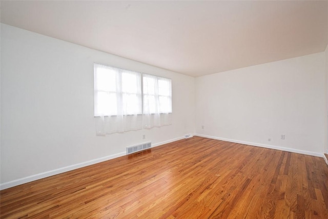 empty room featuring visible vents, baseboards, and wood finished floors